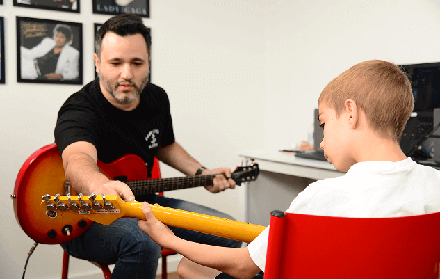 Aula de música - professor ensinando guitarra para aluno